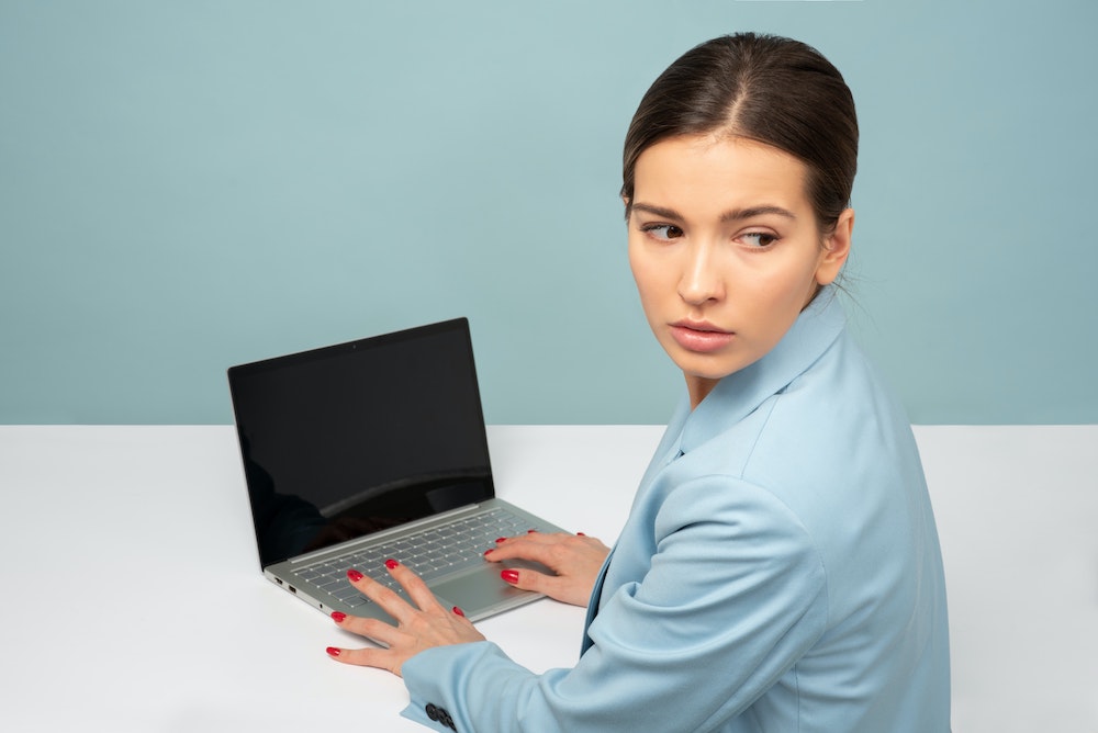Photo of woman at laptop looking worried over her shoulder by Icons8 Team